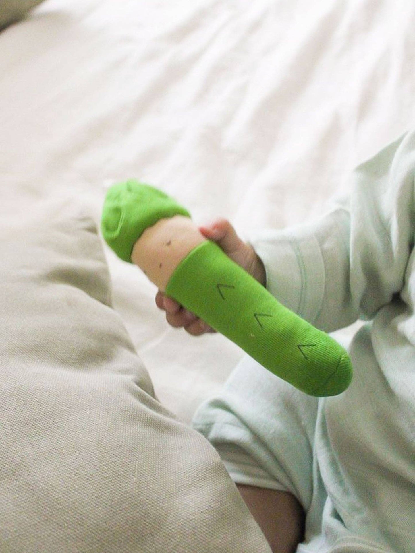 a baby's hand holding an organic plush asparagus