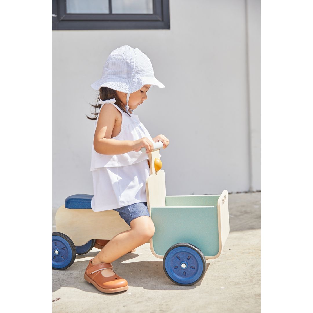 Child playing with a Delivery Bike in Orchard by plan toys