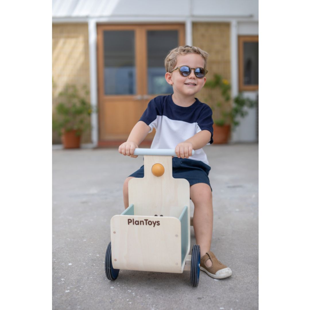 Child playing with a Delivery Bike in Orchard by plan toys