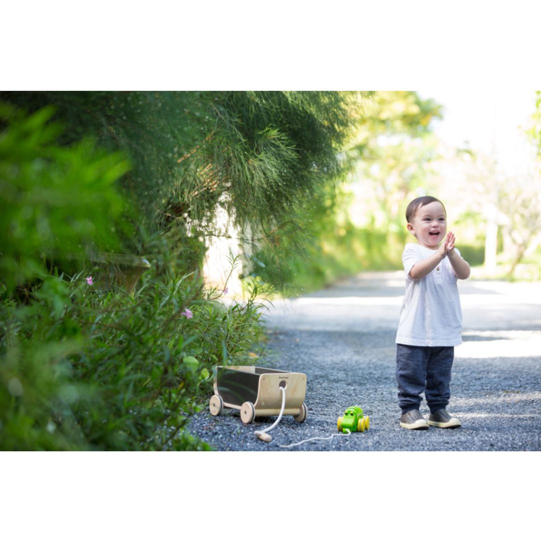 Child playing outside Kids with Black Wagon by Plan Toys