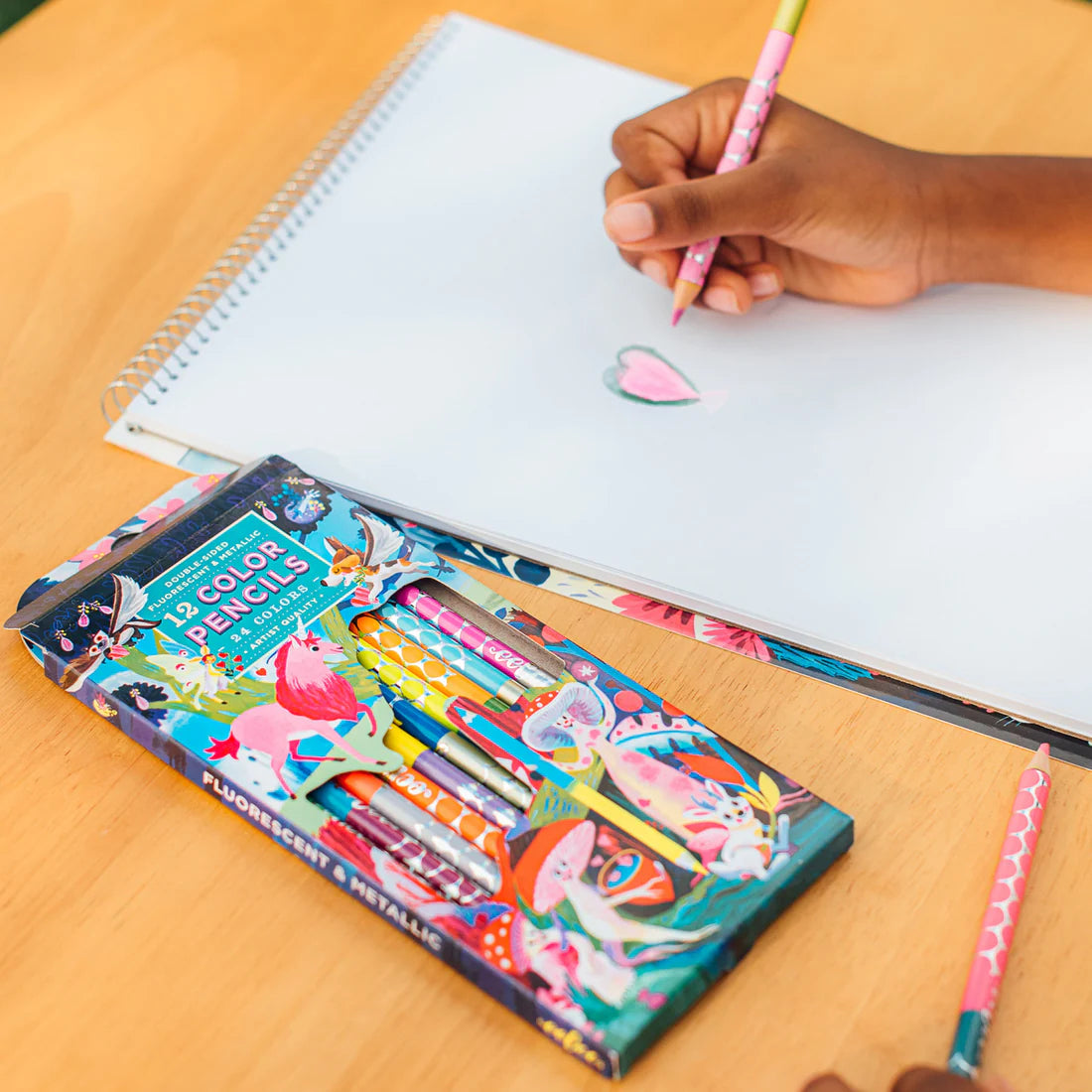 someone drawing a heart on a sketchbook using a magical creature double-sided pencil