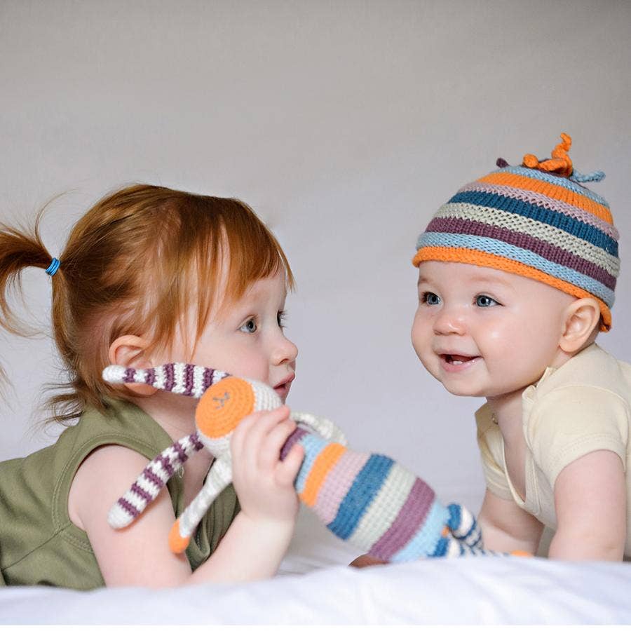 Two children playing with a colorful bunny toy on a bed