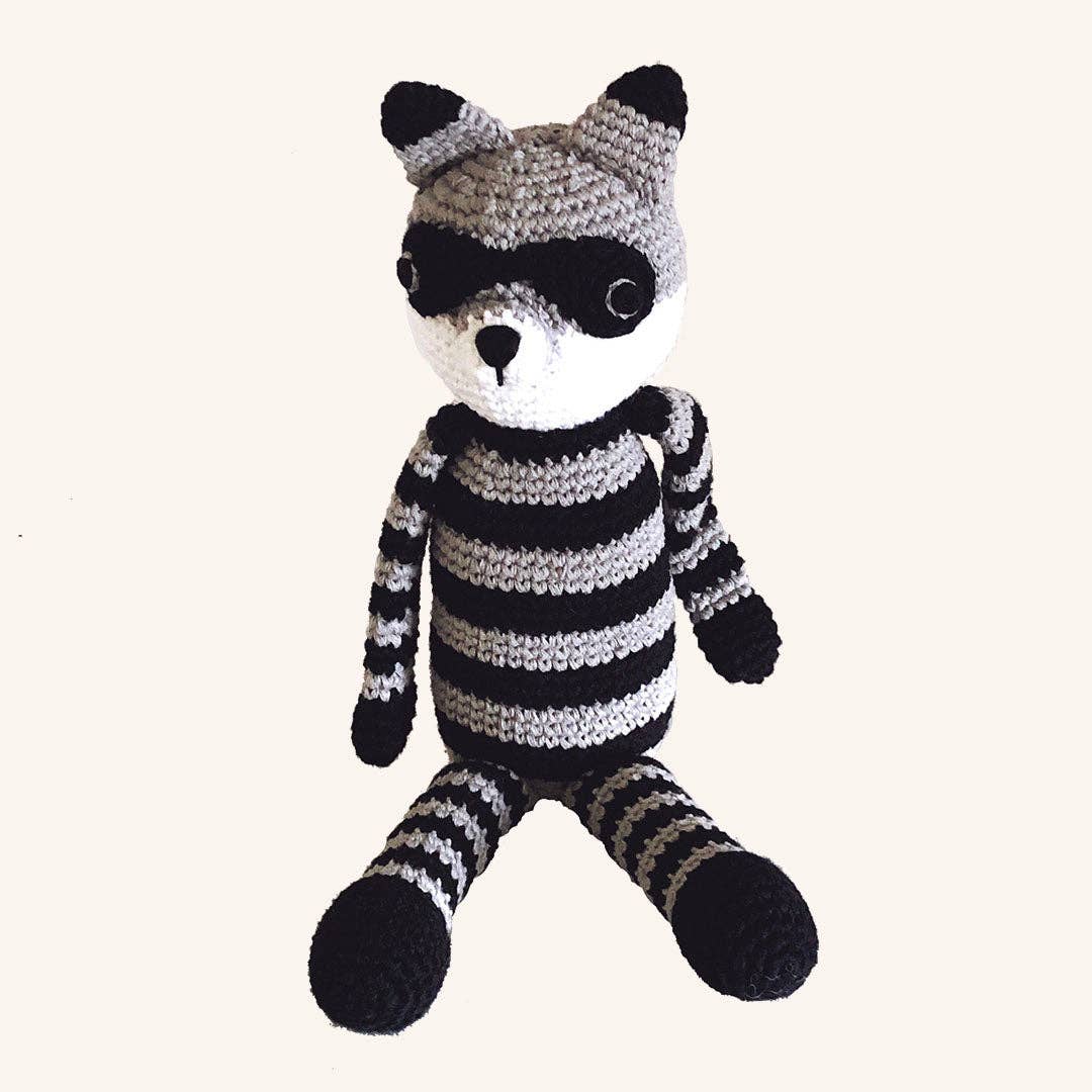 Knitted raccoon toy with black and grey stripes on a white background