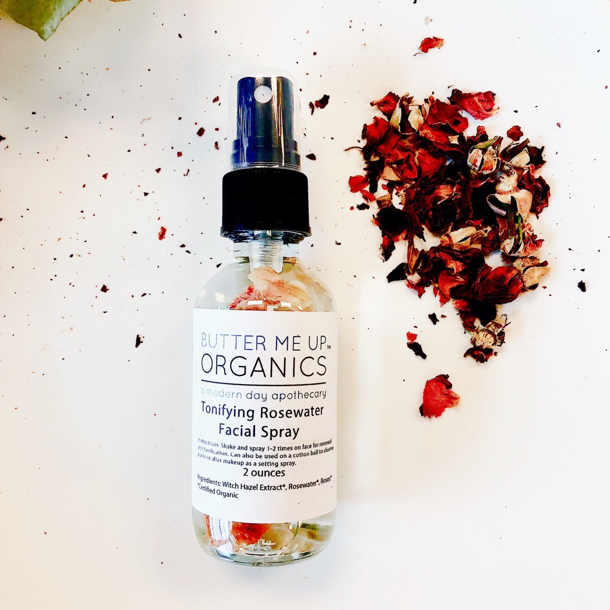 Butter Me Up Organics facial spray bottle with dried flowers on a light background