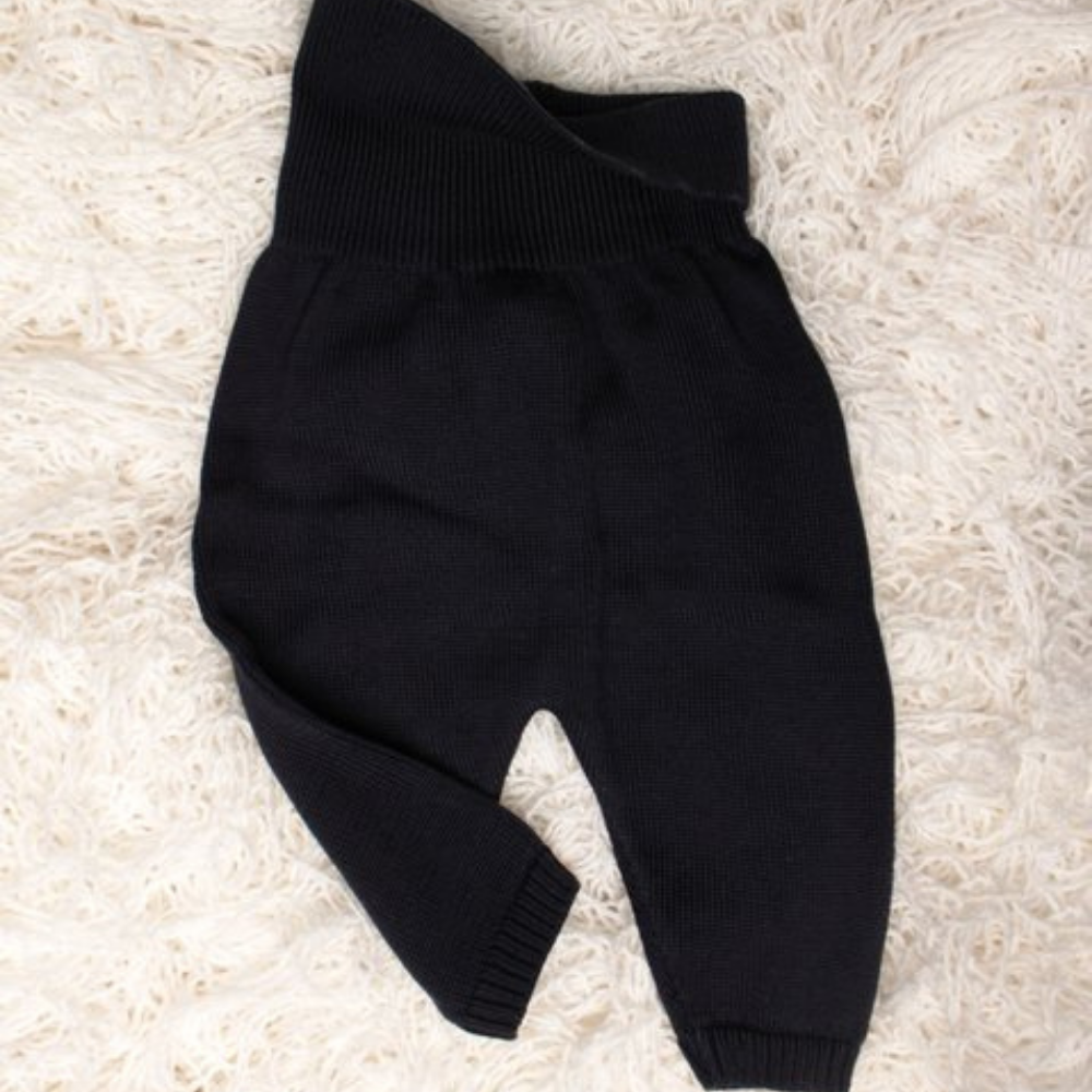 Black baby pants on a beige carpet