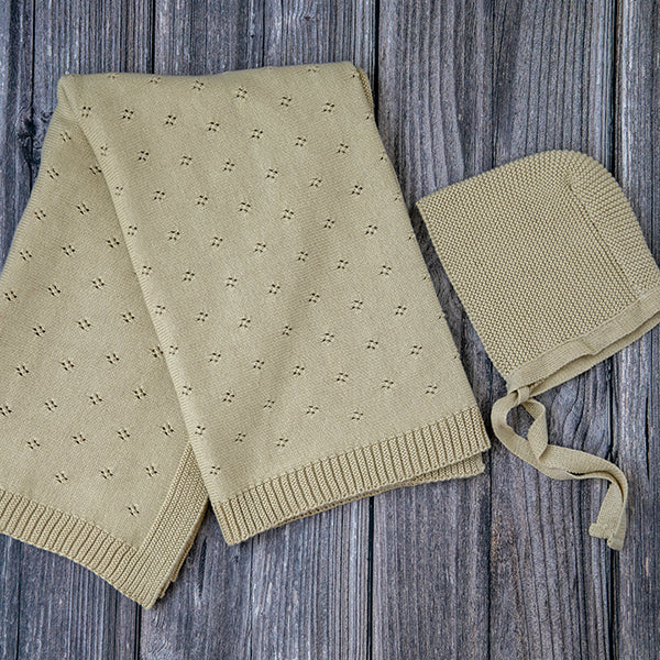 Beige baby blanket and bonnet set on a wooden surface