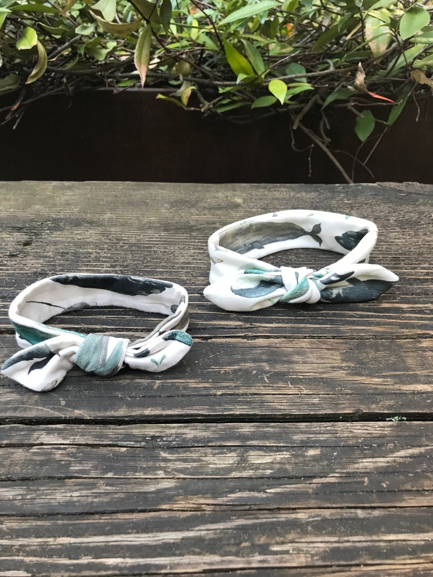 Two Whale Song Baby Head Wraps on a wood bench