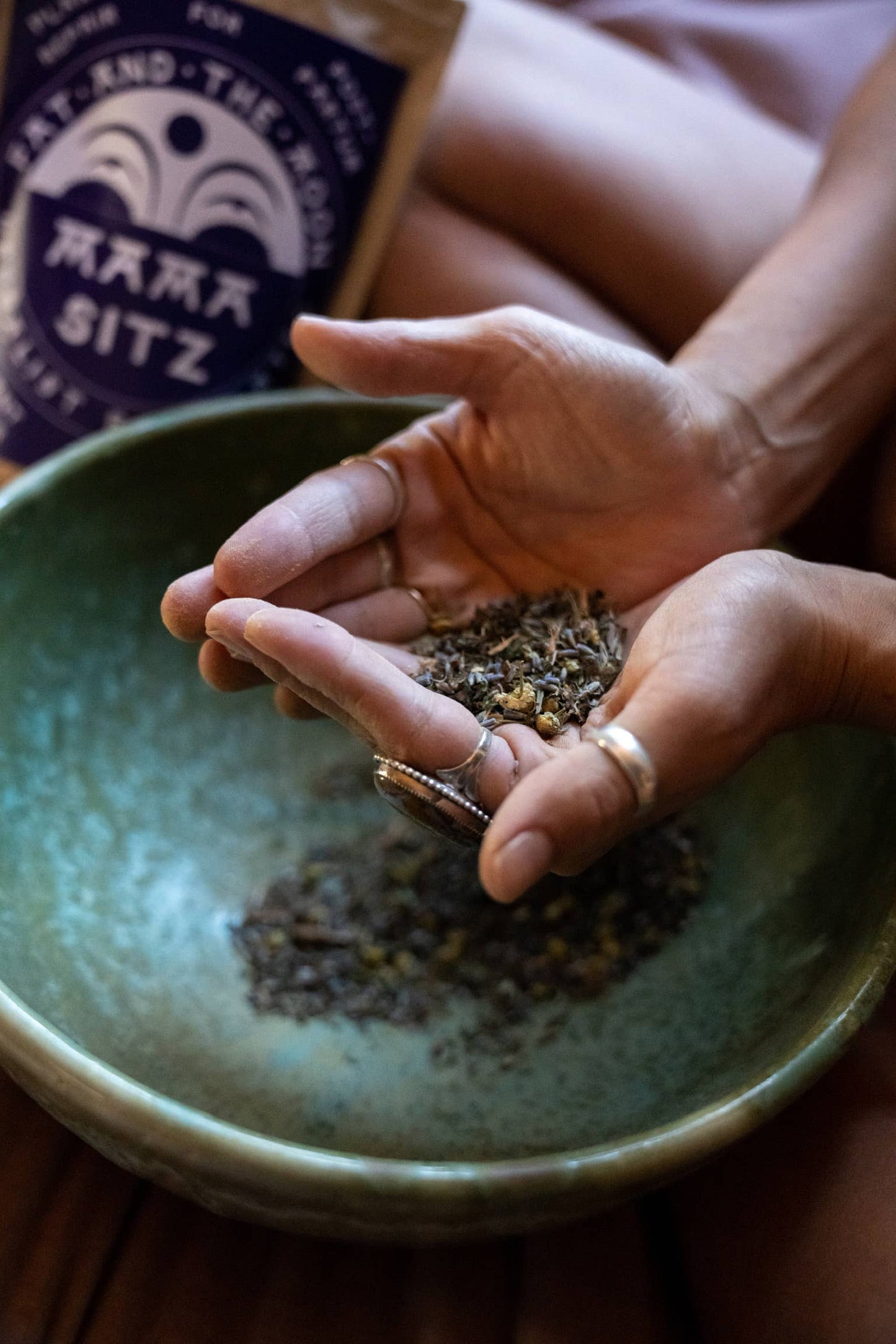 a person picking up a handful of mama sitz from a ceramic bowl