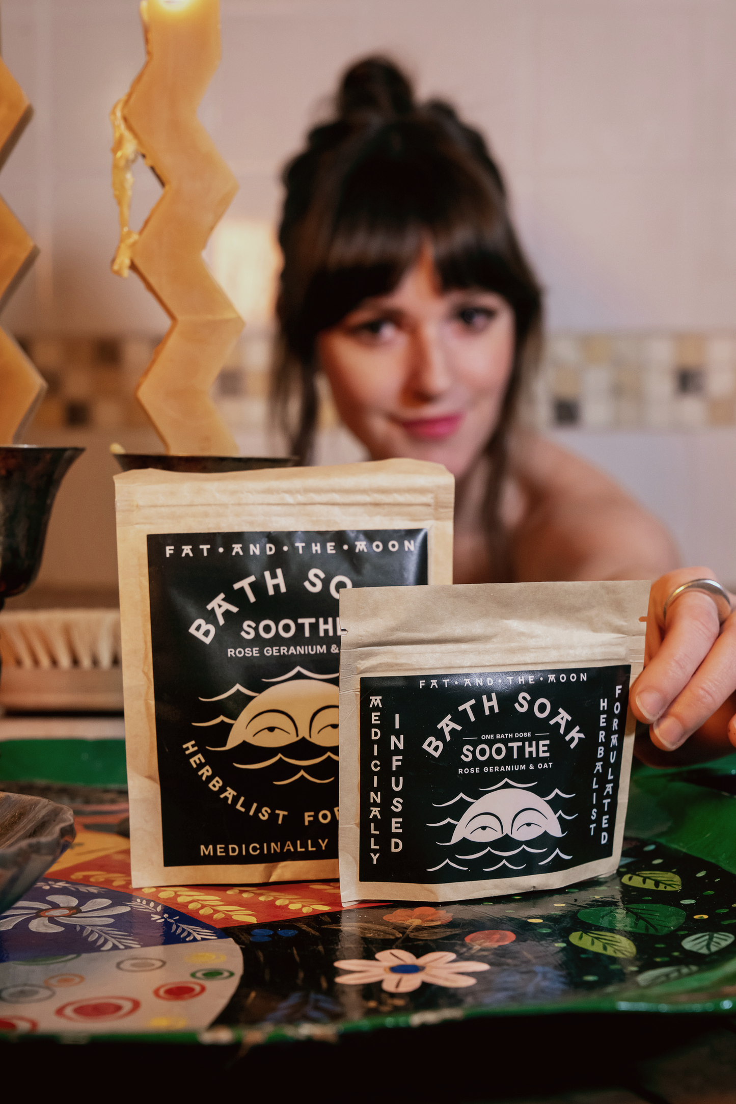a person sitting in a bathtub holding a bag of soothe bath soak