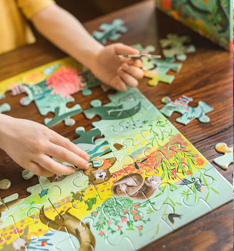 Child building an otter puzzle i=on a wood table