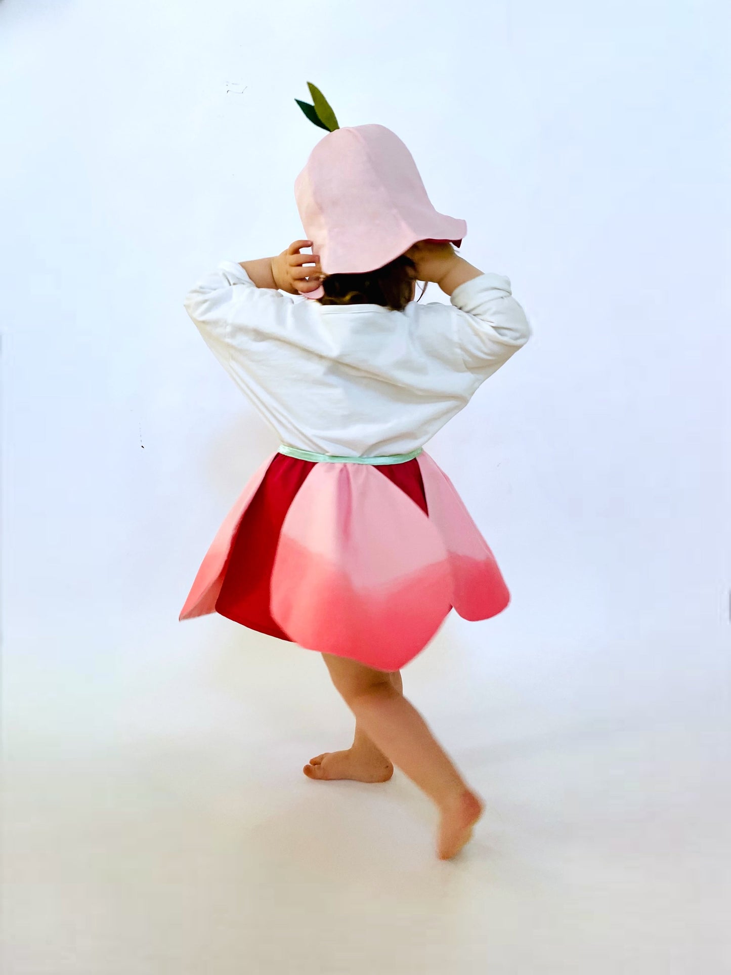 Person wearing a pink and red dress with a white sweatshirt on a white background