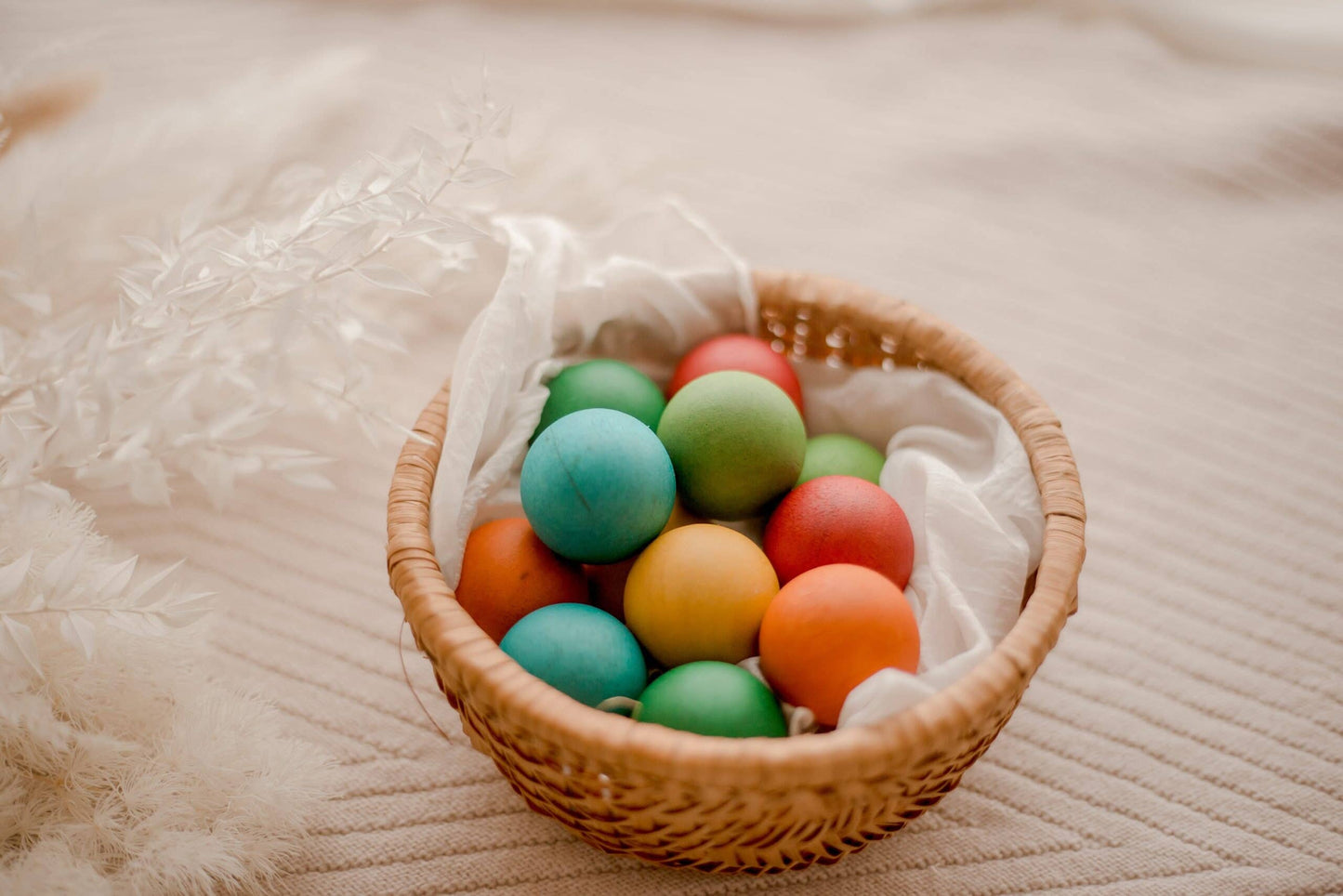 Wicker basket filled with colorful wooden balls on a soft surface