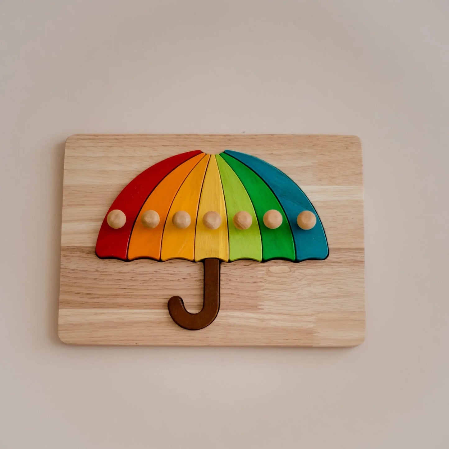 Wooden puzzle shaped like a rainbow umbrella on a beige background