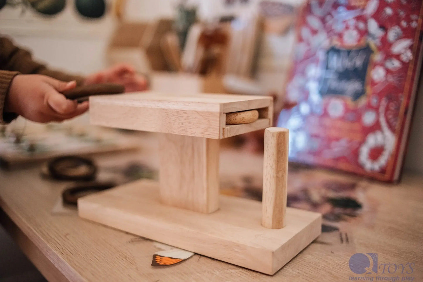 Wooden rings activity puzzle on a table with a child playing with it