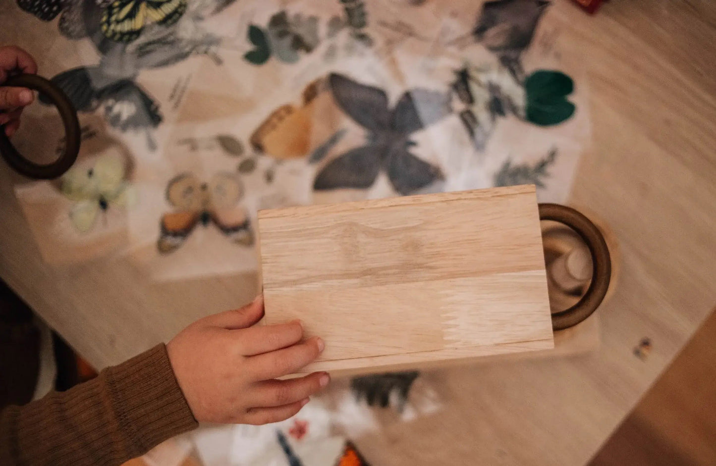 A child playing with a wooden rings activity toy on a table decorated with paper butterflies