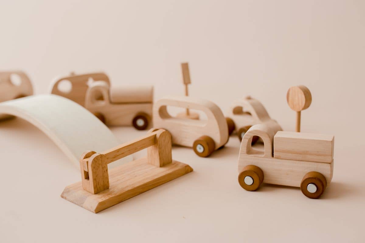 Wooden toy cars, road signs and a bridge on a beige background
