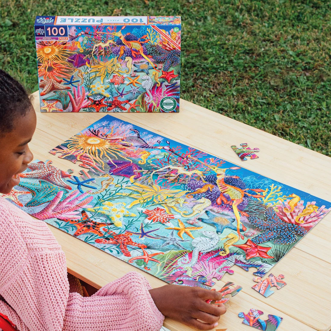 a child making a puzzle on a wooden table outside