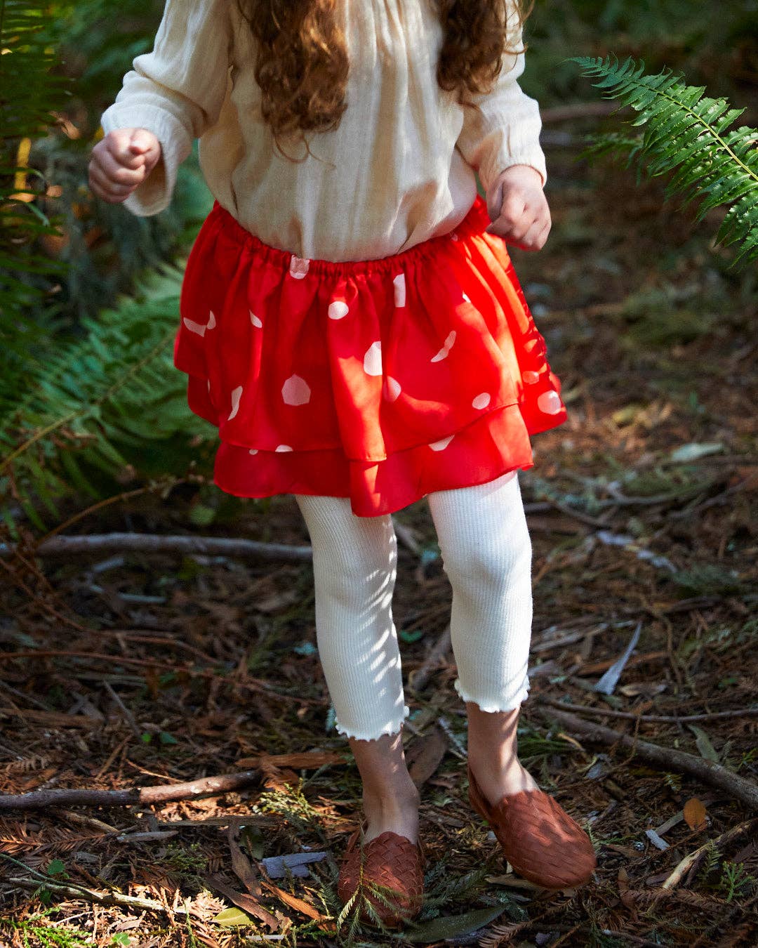 child standing in the woods wearing a mushroom tutu