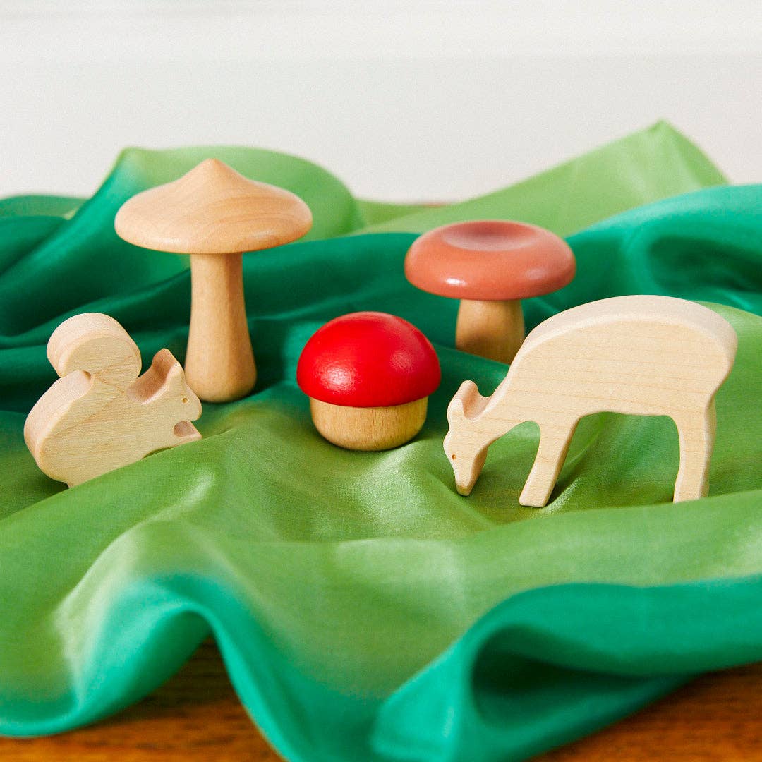 a wooden squirrel, deer, and mushrooms on a forest playsilk