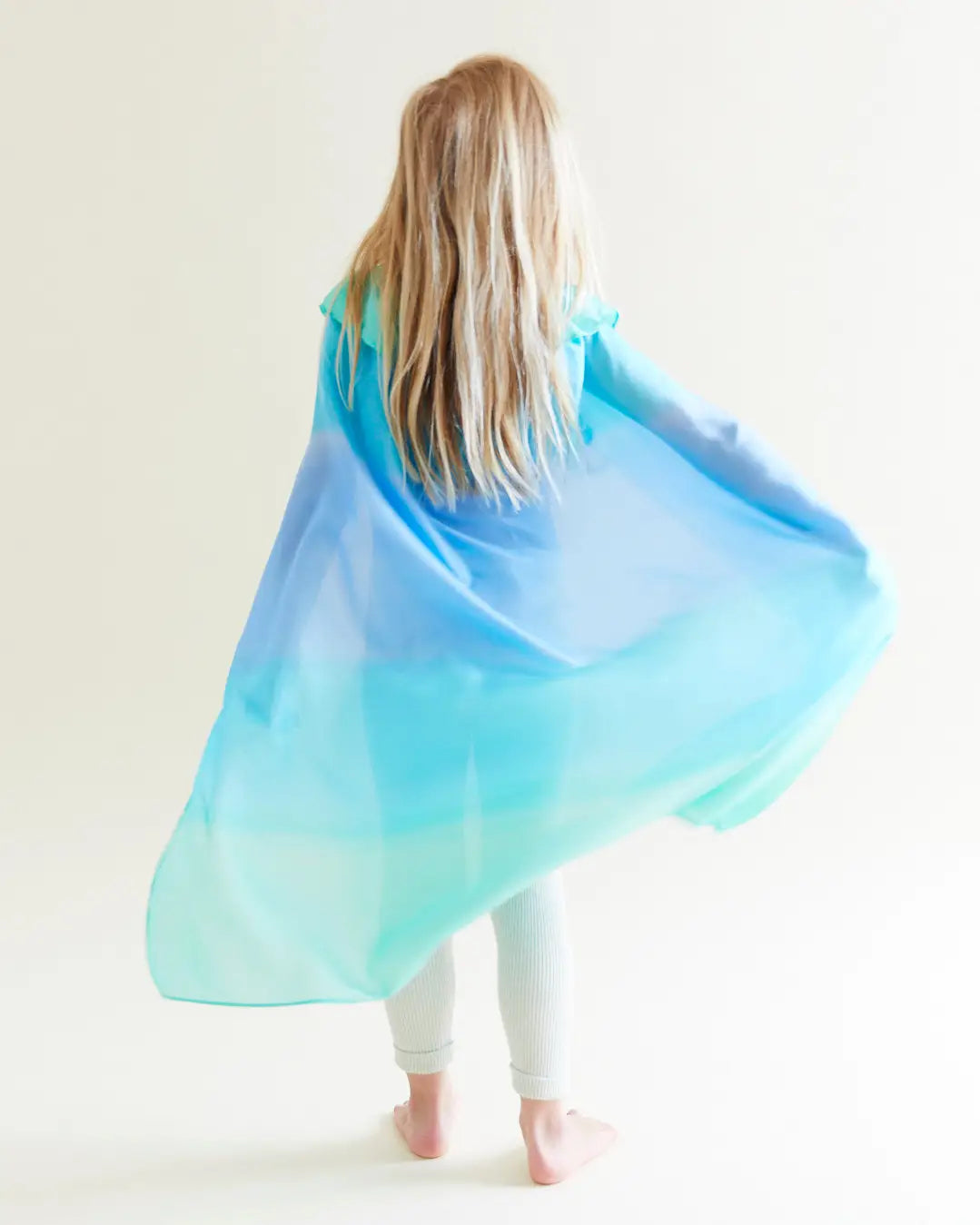 child with their back turned to the camera wearing Mermaid Reversible Silk Play Cape