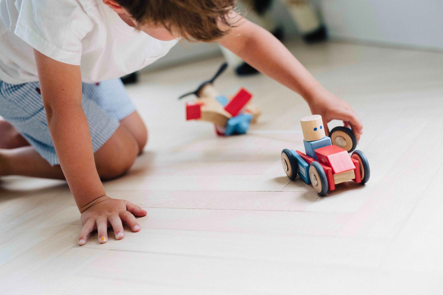 Child playing with dare devil magnetic block set on the floor