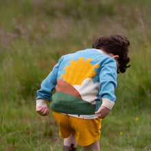 Load image into Gallery viewer, Child walking in a grass field wearing From One To Another Sunshine Design Knitted Cardigan
