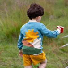 Load image into Gallery viewer, Child walking in a grass field holding a red cup wearing From One To Another Sunshine Design Knitted Cardigan
