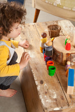 Load image into Gallery viewer, A child playing with colorful wooden peg people and rainbow wooden cups on a wood table
