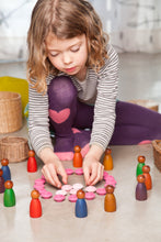 Load image into Gallery viewer, A child playing on the floor with colorful peg people, straw baskets, and a pink wooden flower mandala
