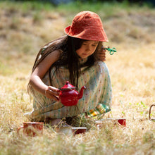 Load image into Gallery viewer, Child plating with a tea set in a grass field wearing Cherries Reversible Sunhat in Olive
