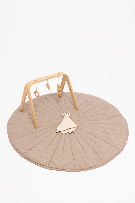 Round beige play mat with wooden baby gym on a white background