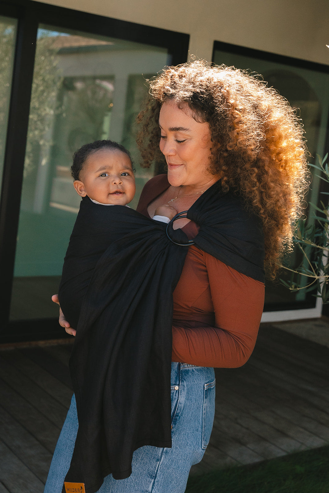 Woman holding a baby in a sling outdoors
