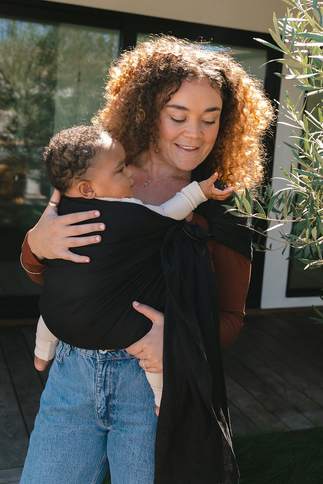 Woman holding a child in a sling outdoors