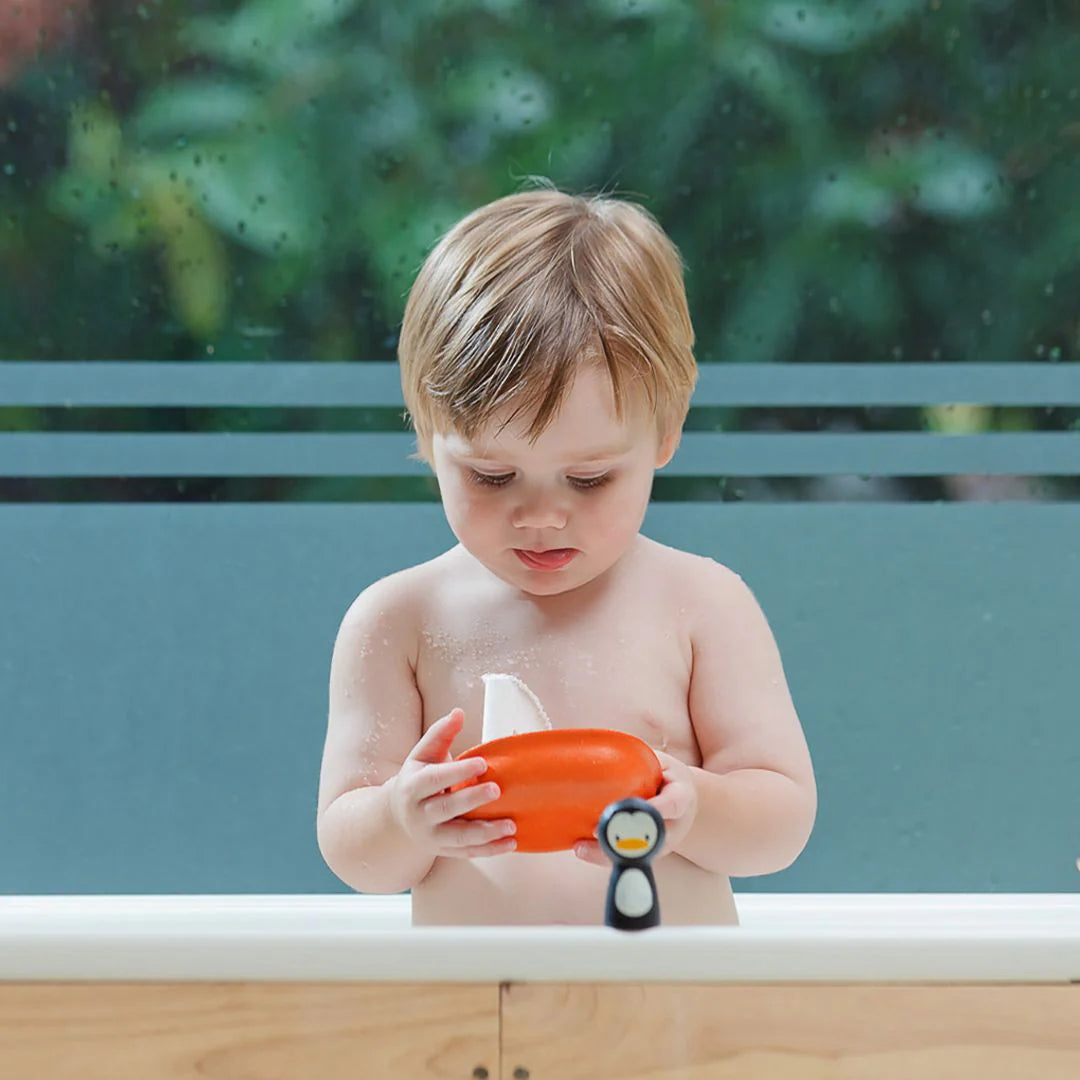 Child playing with a toy boat in a bathtub outdoors