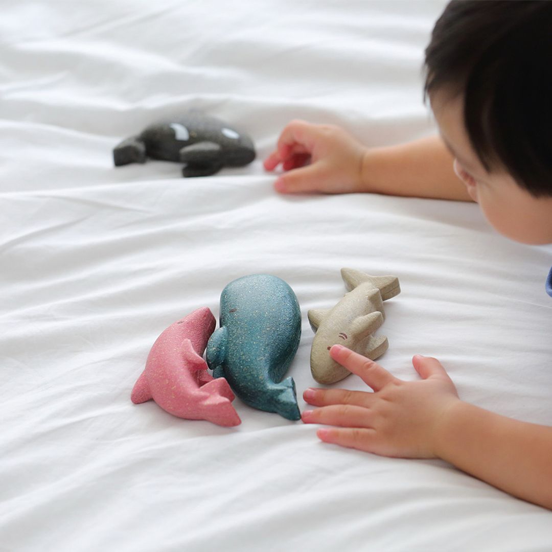 Children's hands interacting with colorful animal-shaped toys on a white surface