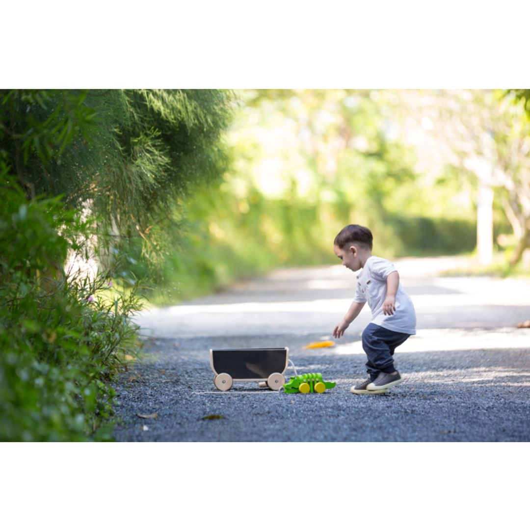 Child playing outside Kids with Black Wagon  by Plan Toys