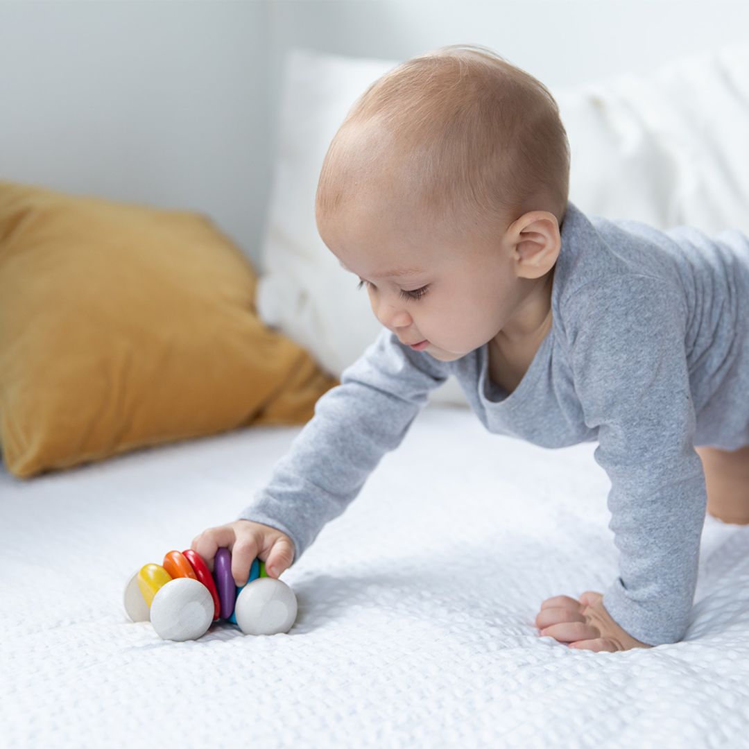 Baby playing with a colorful toy on a bed
