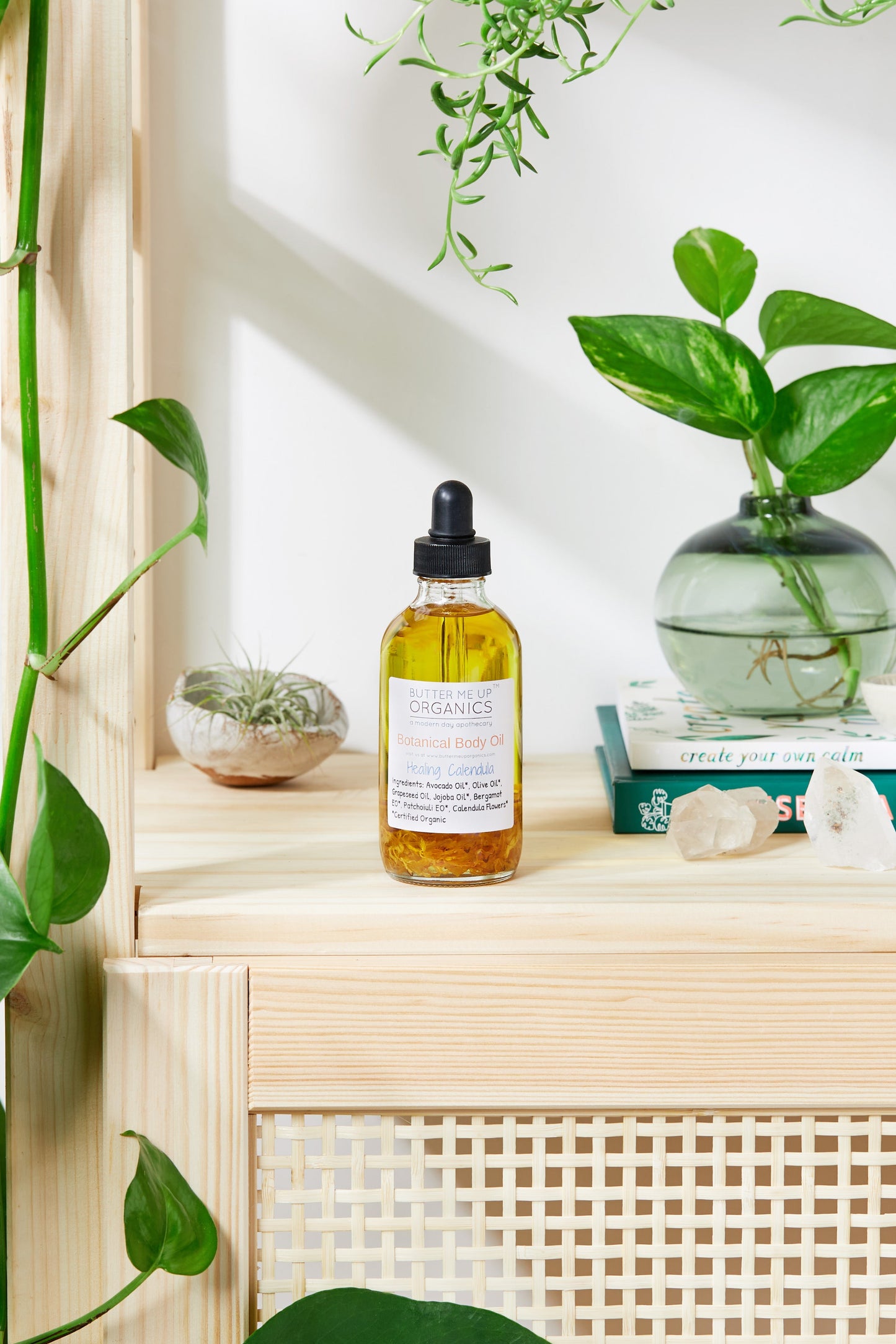 Bottle of oil on a wooden shelf with plants and books in the background