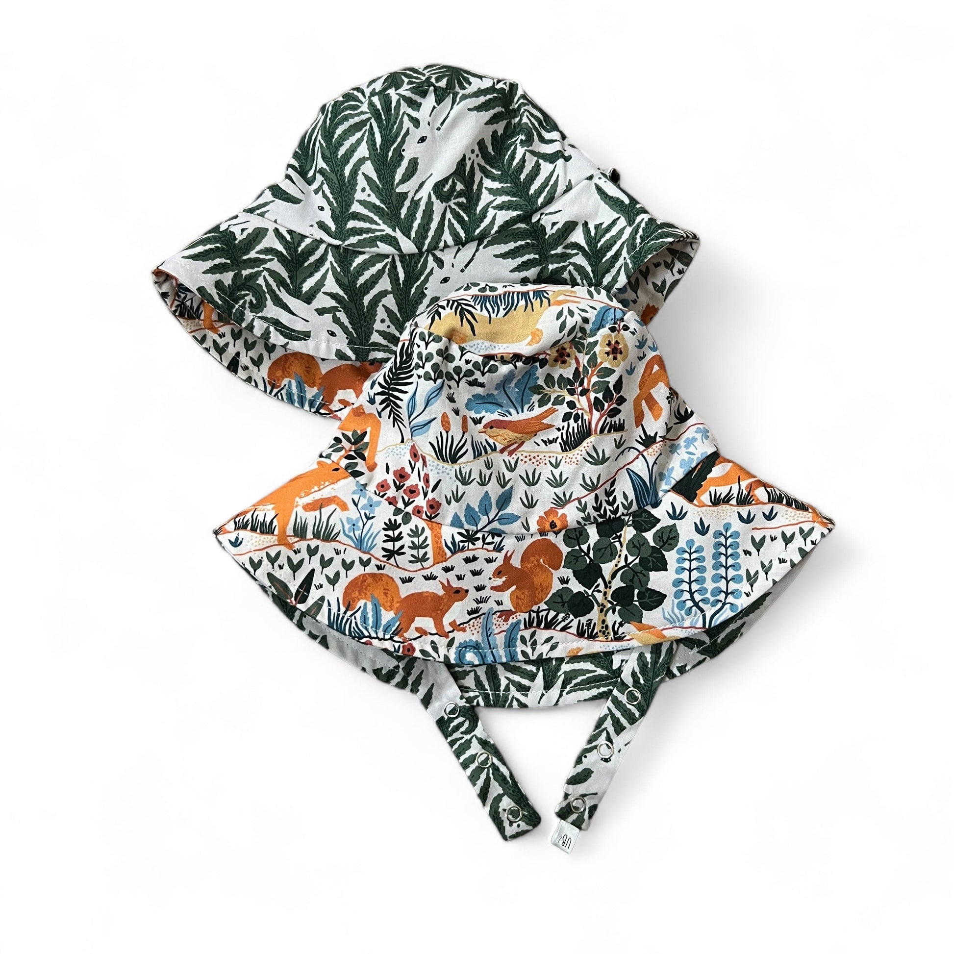 Two hooded cloaks with nature-themed designs on a white background