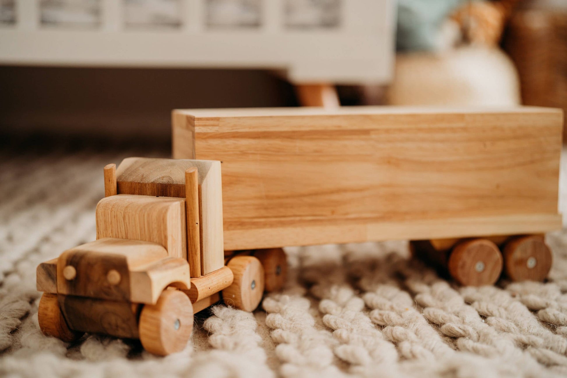 Wooden toy truck on a textured surface with a blurred background