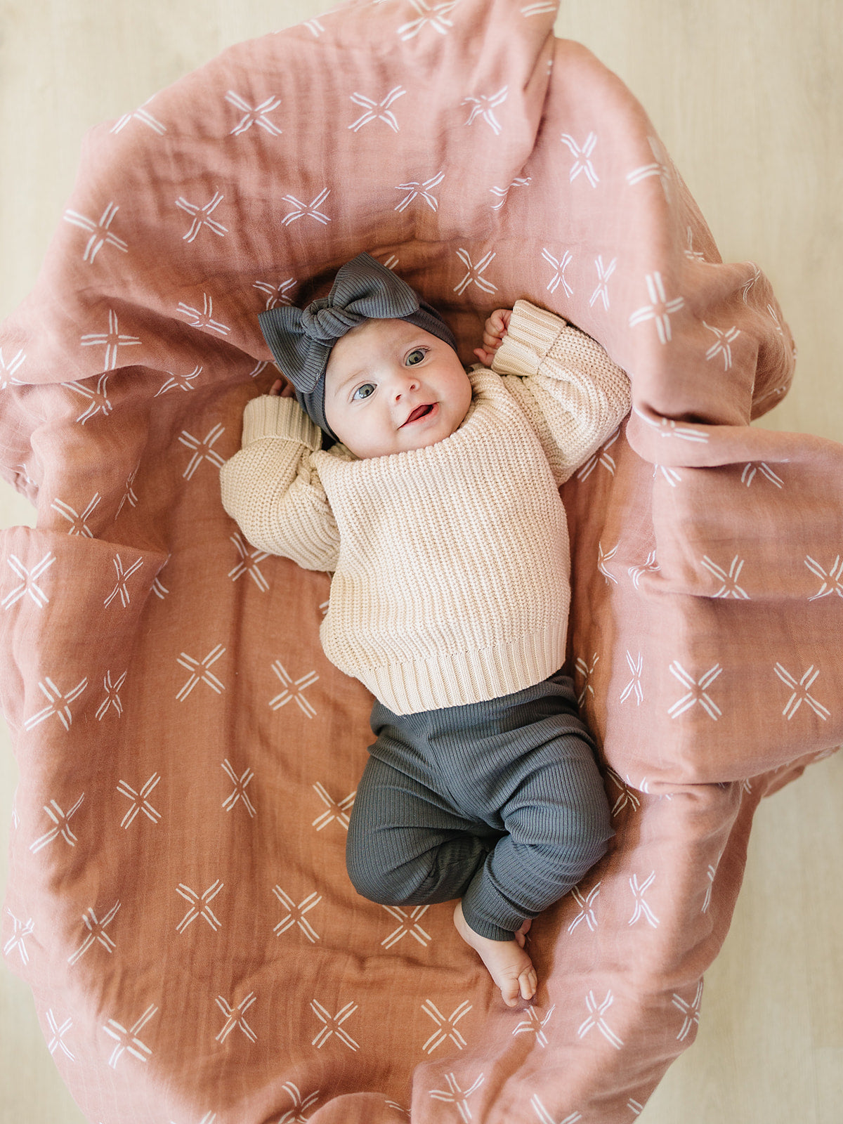 Baby lying on a pink cushion with a patterned background