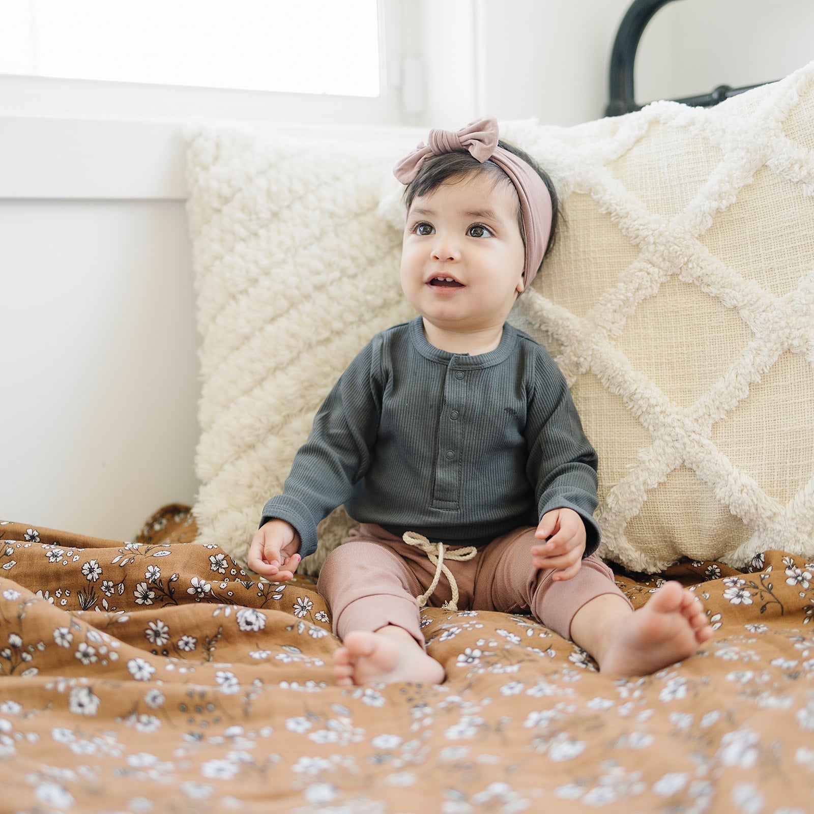 Baby sitting on a floral blanket with a neutral background