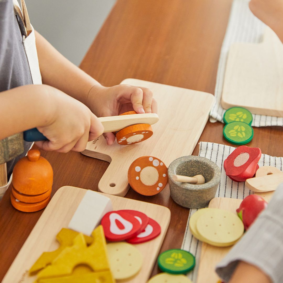 Children playing with wooden kitchen toys on a wooden table