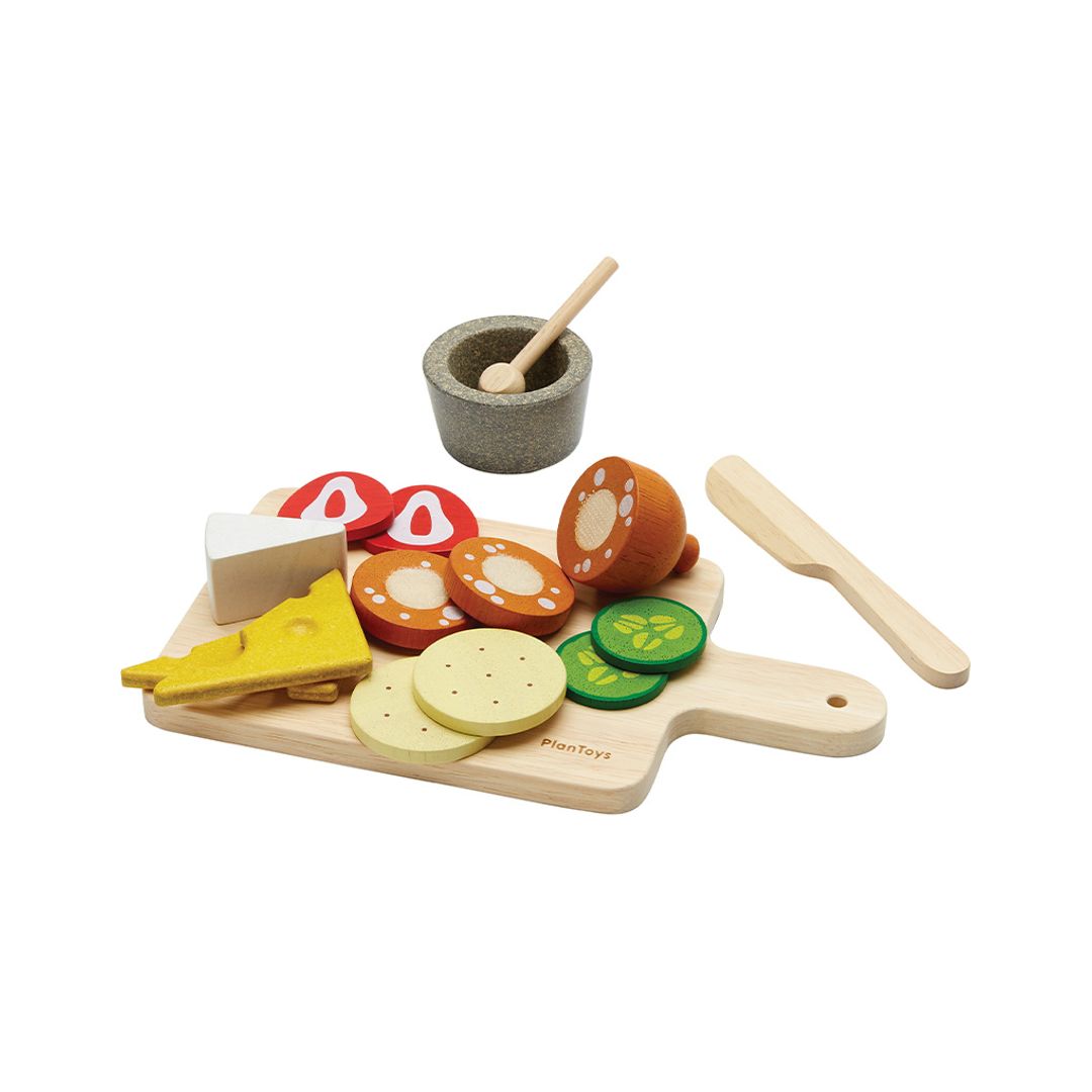 Wooden toy food set with cutting board, vegetables, and utensils on a white background