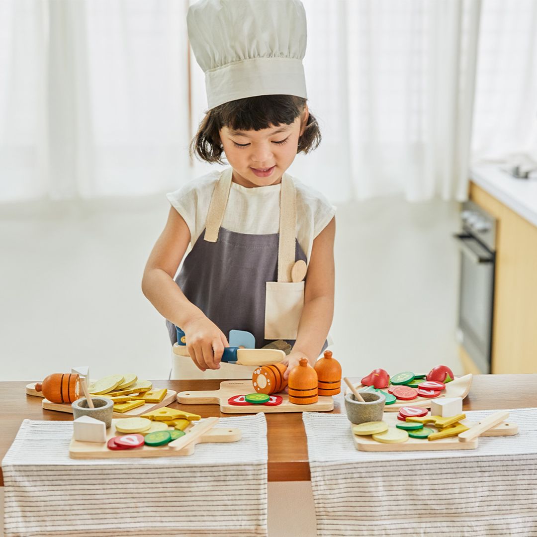 Child playing with wooden kitchen toys in a kitchen setting