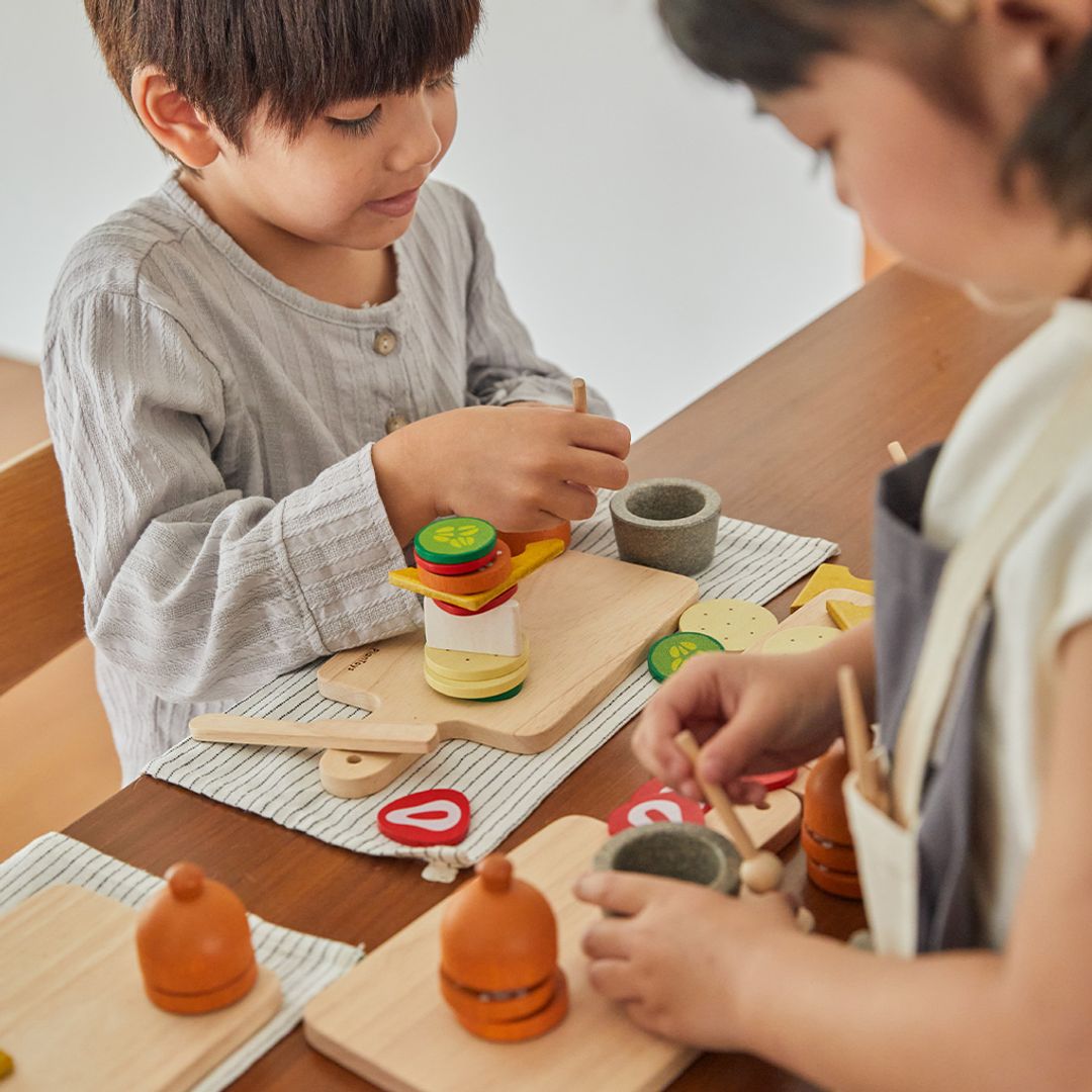 Two children playing with wooden toys at a table.
