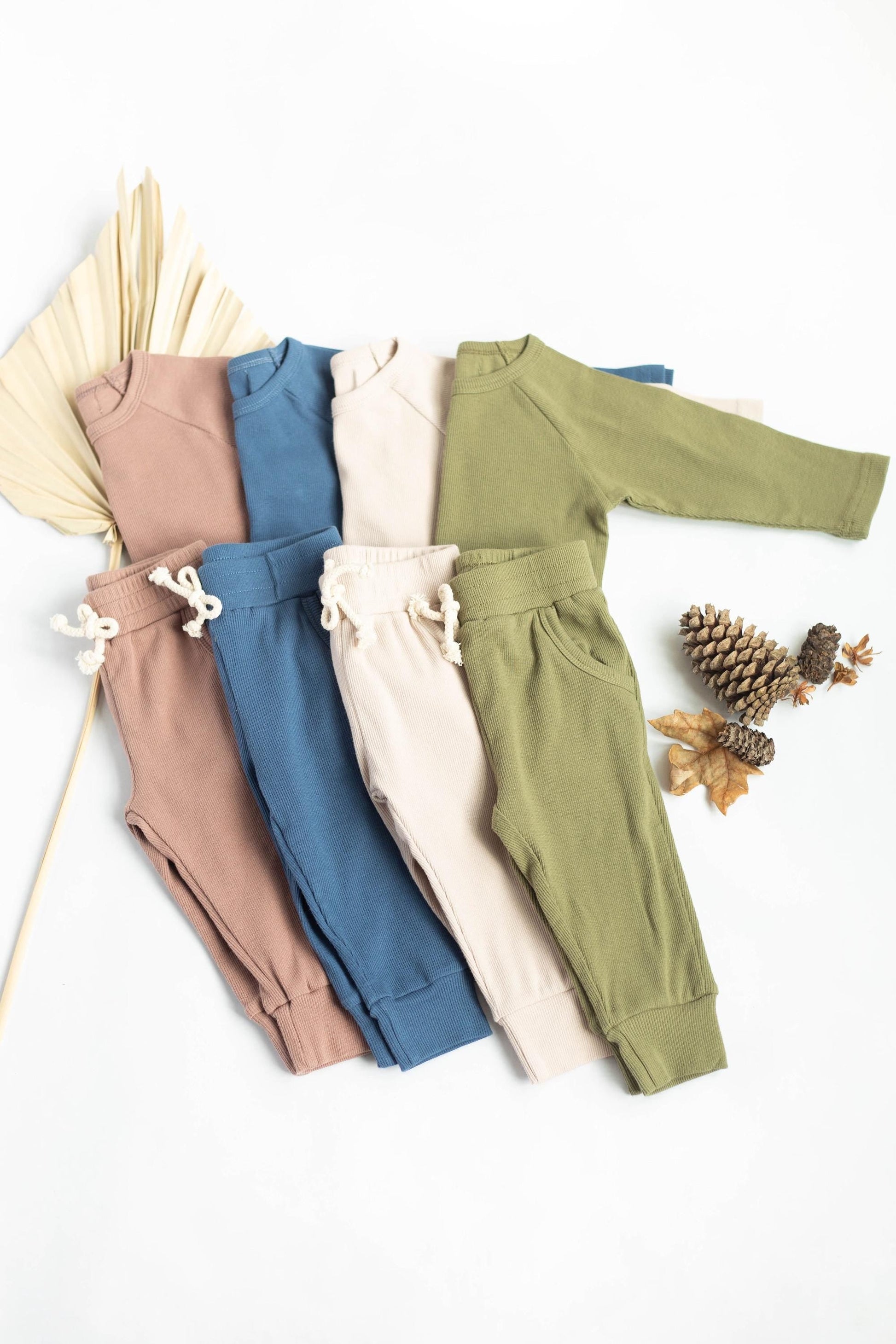 Set of colorful baby outfits with ruffled details on a white background.