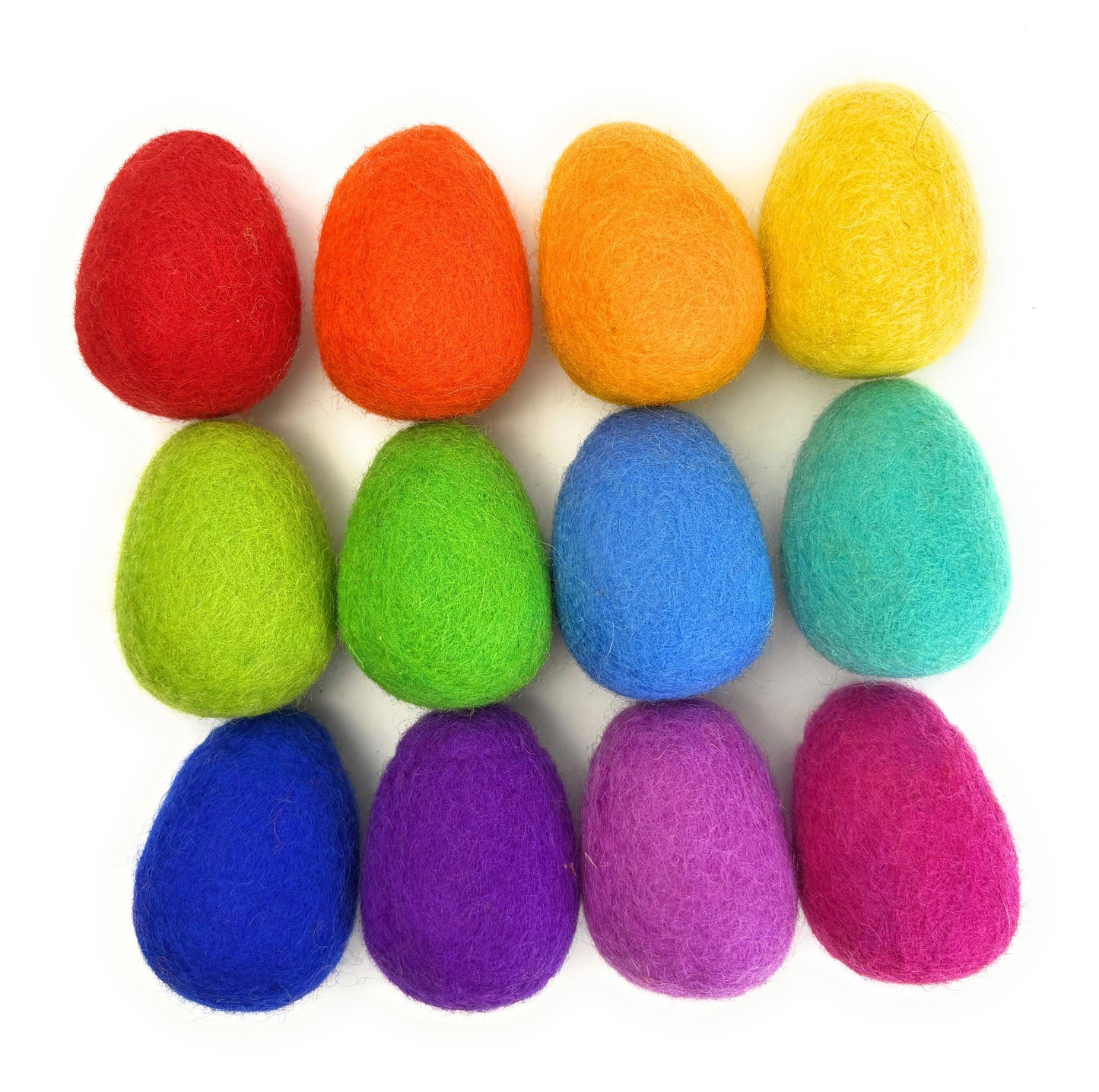 Colorful felt eggs in a rainbow pattern on a white background