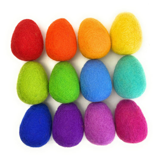 Colorful felt eggs in a rainbow pattern on a white background
