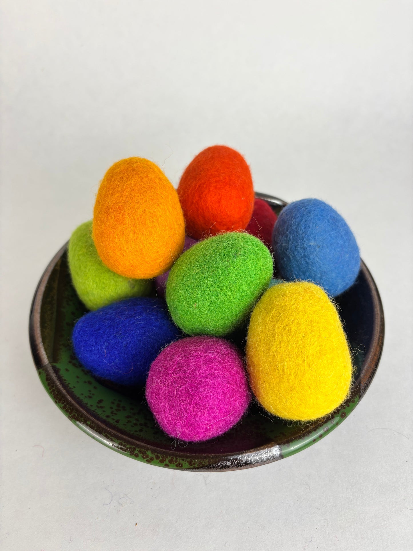 Colorful felted wool balls in a bowl on a white background